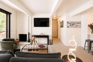 A modern living room with a fireplace, a flat-screen TV, and a seating area with a coffee table. - Central Aspen Condo - Prime Price and Location (Aspen)