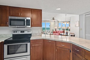 A kitchen with wooden cabinets, a stainless steel microwave, and an oven.