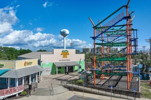 A theme park entrance with a play area, a water tower, and a building labeled 'Adventure Zone'.