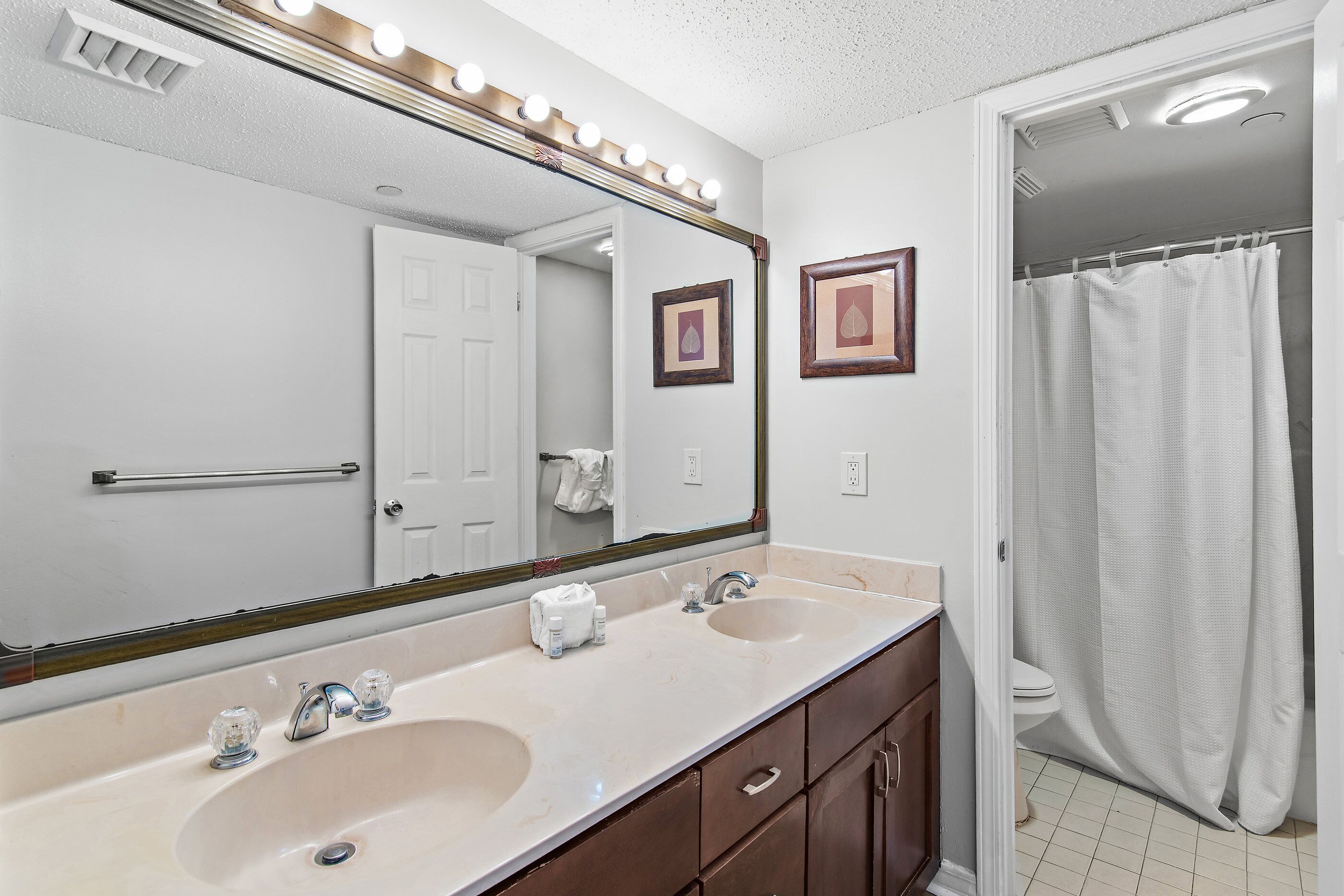 A bathroom with a double sink, a large mirror, and a shower curtain.