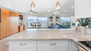 Una cocina moderna con una isla grande, armarios blancos e iluminación colgante.