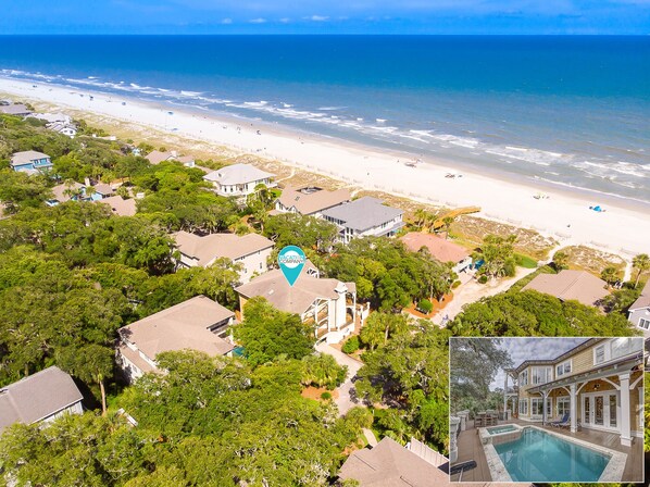 A coastal property with a beach view, a swimming pool, and a mix of residential and commercial buildings.