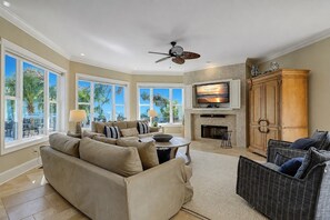 A spacious living room with a large sofa, a television mounted above a fireplace, and a ceiling fan. - 31 Mallard Rd-2nd Row(140 steps) to the Ocean, Private Pool & Spa (Hilton Head Island)