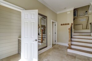 Un couloir avec une porte blanche, un miroir, un escalier et un panneau indiquant « PLAGE » sur le mur.
