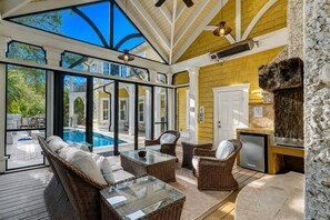 A sunlit patio with wicker furniture, a pool, and a stone wall. - 31 Mallard Rd-2nd Row(140 steps) to the Ocean, Private Pool & Spa (Hilton Head Island)