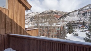 A wooden balcony with a view of a snowy mountain town. - Pet Friendly 2-bedroom, 2-bathroom condo, Manitou #101 and those views! (Telluride)