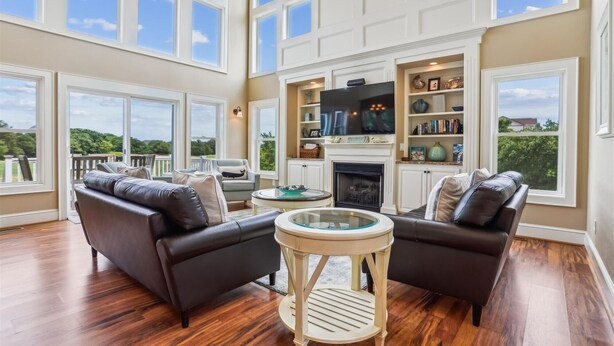 A spacious living room with a fireplace, large windows, and a balcony. - Golf Front, Premium built. Pool, hot tub, gameroom, theater room. Dogs ok. (Corolla)