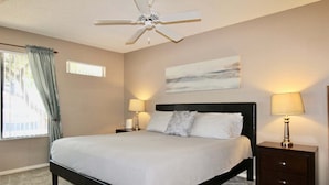A bedroom with a bed, two bedside tables with lamps, a ceiling fan, a window with curtains, and a painting on the wall. - Endless Summer Modern 2 Bedroom Condo/ Community Pool/ Jacuzzi/ Scottsdale (Scottsdale)
