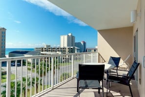 A balcony with a view of the ocean and cityscape, featuring a table and chairs. - Crystal Tower 407 - Beachfront pool, great amenities & private skywalk to beach! (Gulf Shores)