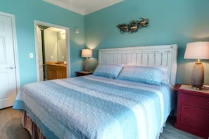 A bedroom with a bed, a nightstand, a dresser, and a mirror. - Crystal Tower 407 - Beachfront pool, great amenities & private skywalk to beach! (Gulf Shores)