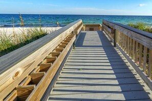 Una pasarela de madera que conduce a una playa con agua azul cristalina.