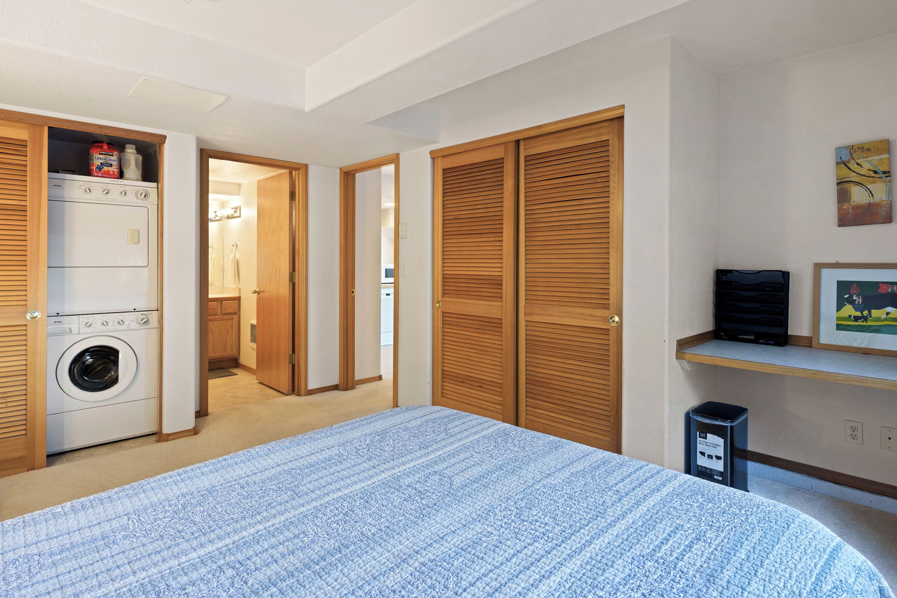 A bedroom with a bed, a washing machine, and a closet.
