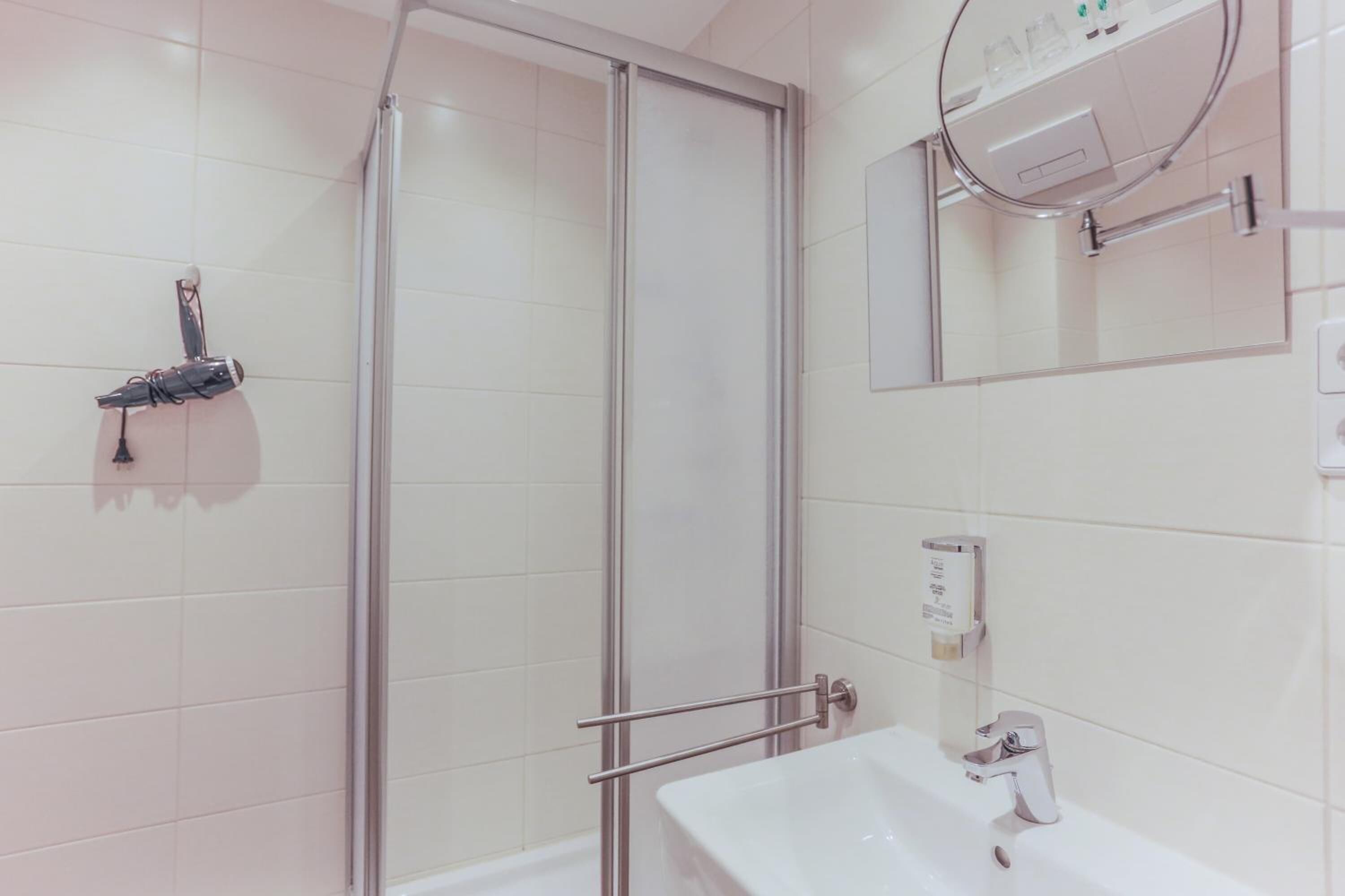 Une salle de bain moderne avec une douche à parois de verre, un lavabo blanc et un miroir.