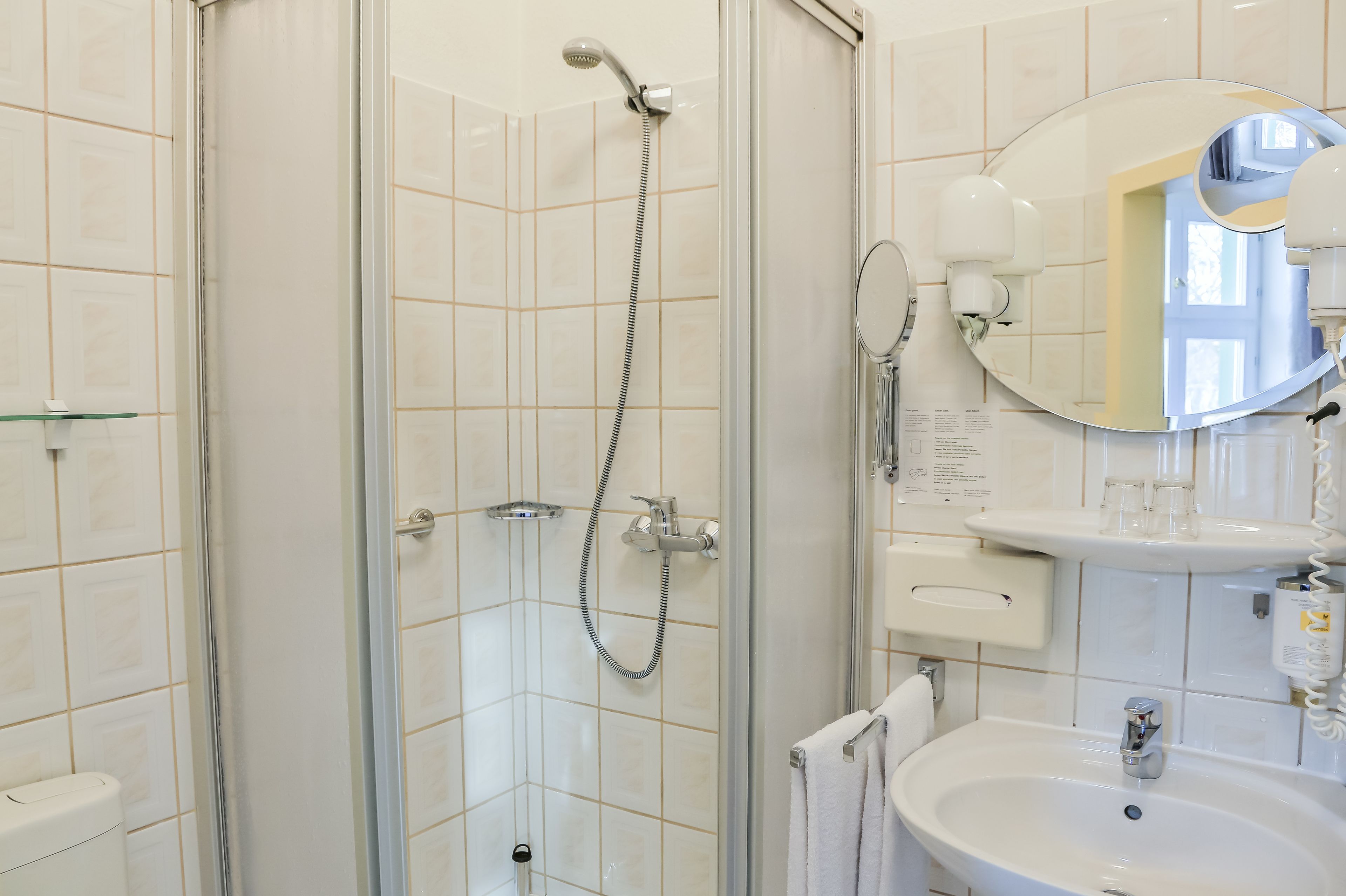 A modern bathroom with a glass-enclosed shower, a sink with a mirror, and a toilet.
