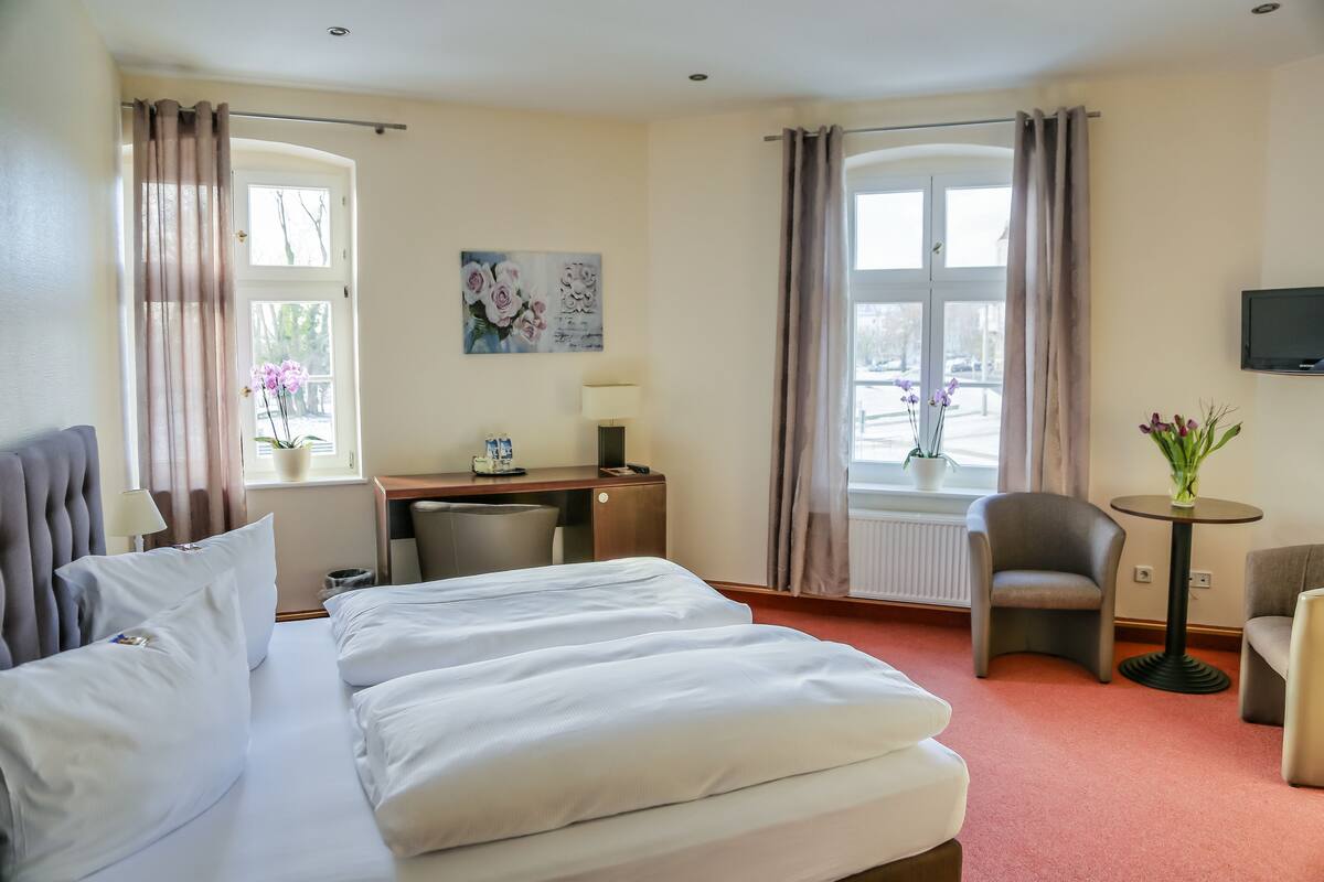 Une chambre d’hôtel équipée d’un lit, d’un bureau, d’une chaise et d’un téléviseur.