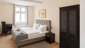 A bedroom with a bed, bedside table, lamp, wardrobe, desk, chair, and a window. - Hotel Zur Alten Oder Frankfurt (Frankfurt an der Oder)