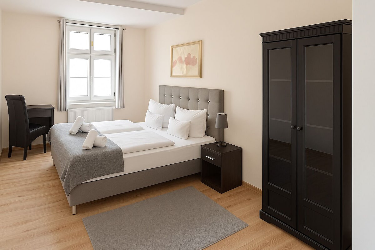 Une chambre à coucher comprenant un lit, une table de chevet, une lampe, une armoire, un bureau, une chaise et une fenêtre.