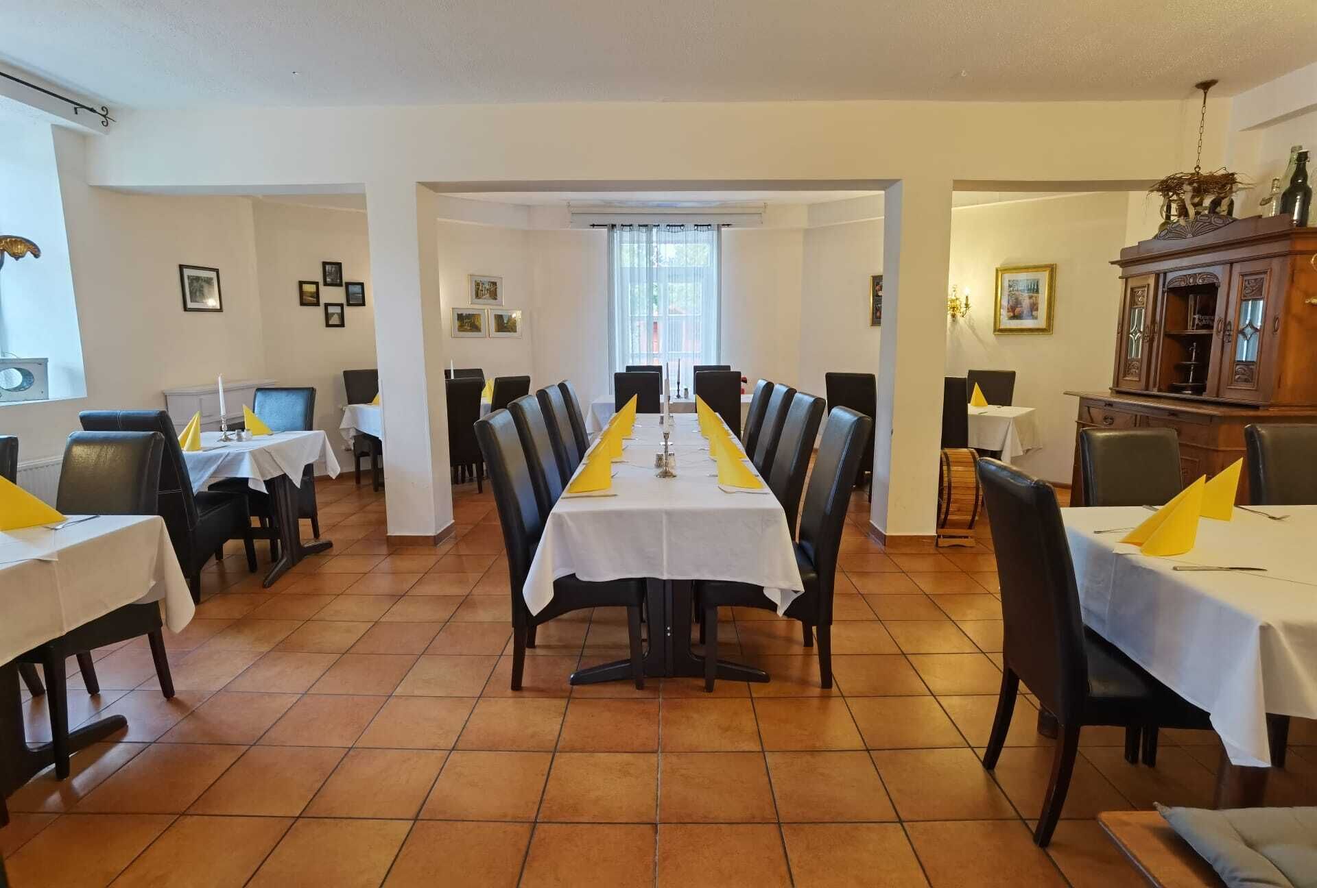 Un comedor con una larga mesa dispuesta para una comida, rodeada de sillas.