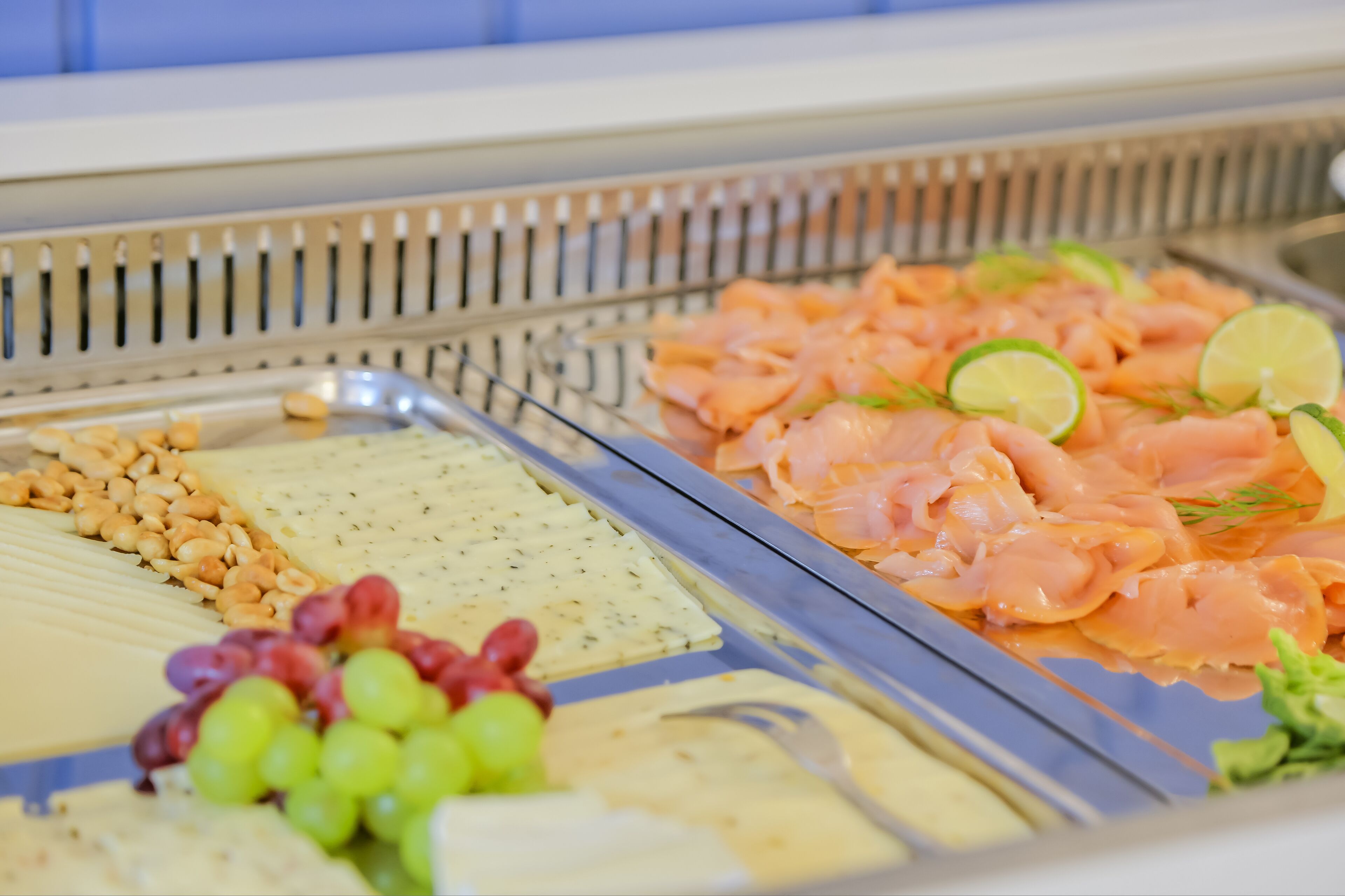 A buffet with various food items including cheese, salmon, and grapes.