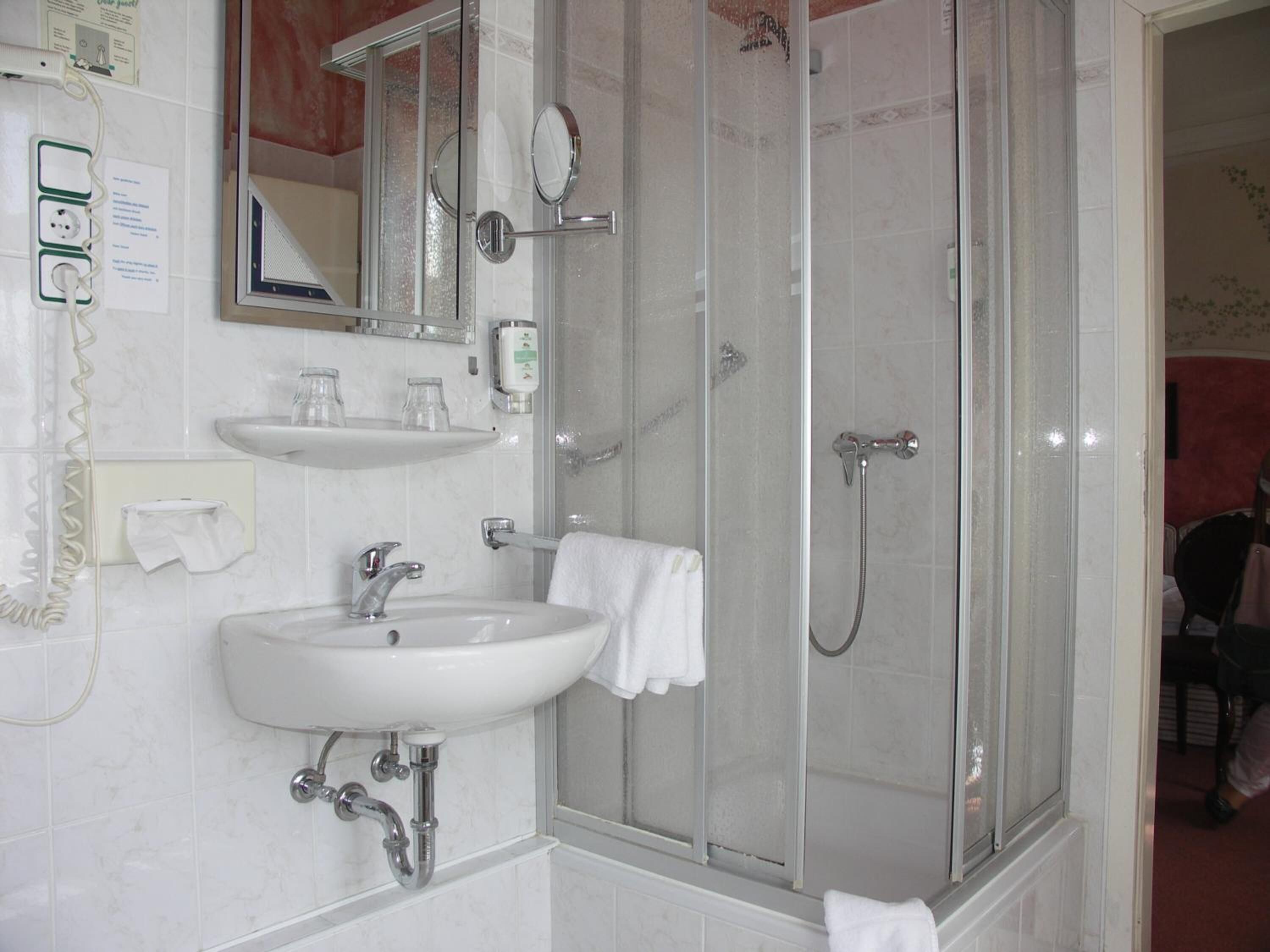 A bathroom with a sink, mirror, and shower.