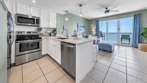 Una cocina moderna con electrodomésticos de acero inoxidable, una isla central y vistas a un balcón con una silla.
