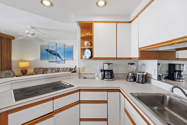 Una cocina moderna con estufa integrada, cafetera y lavaplatos.