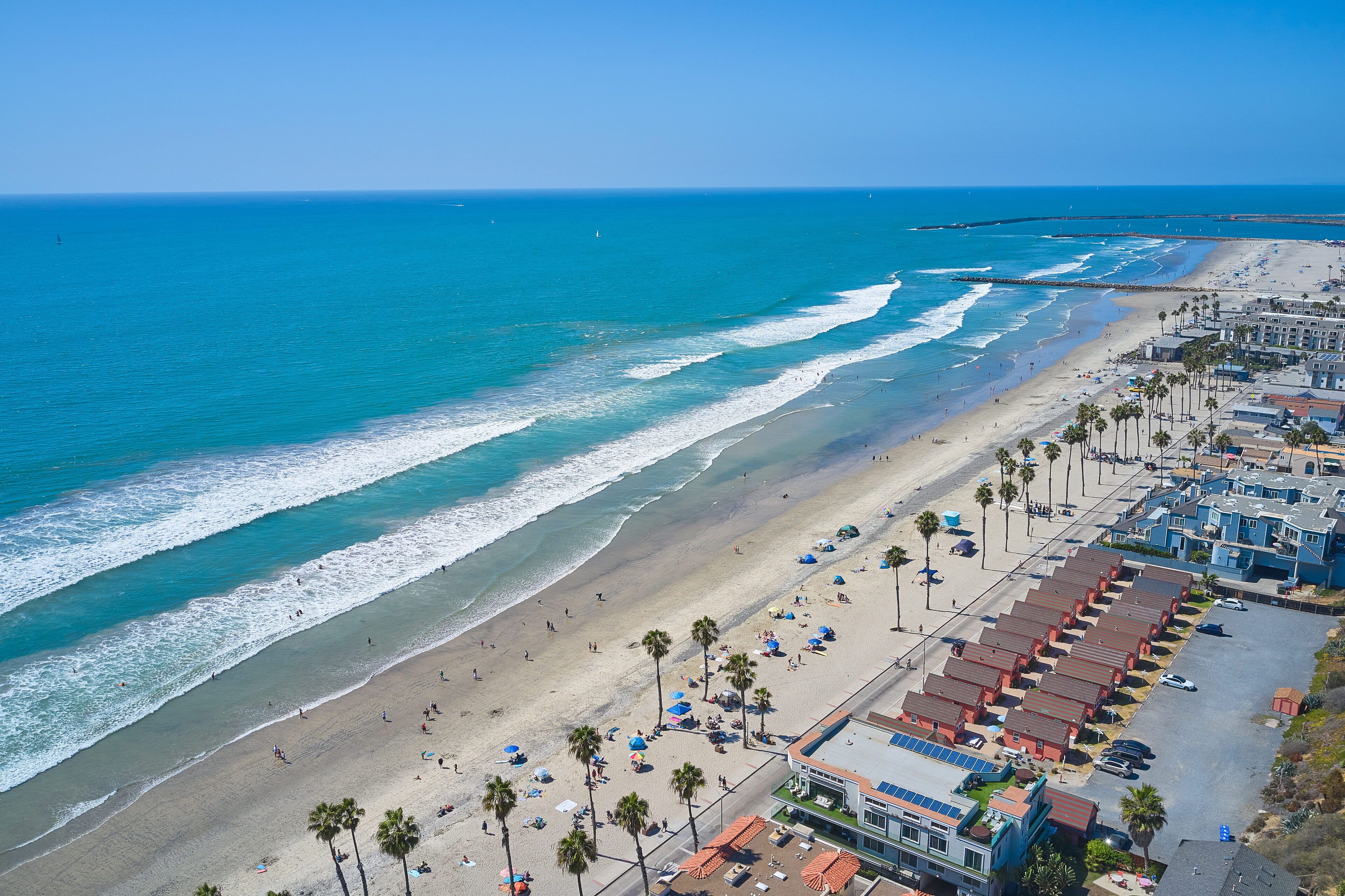 A beachside hotel with multiple rooms, a sandy beach, and a view of the ocean.