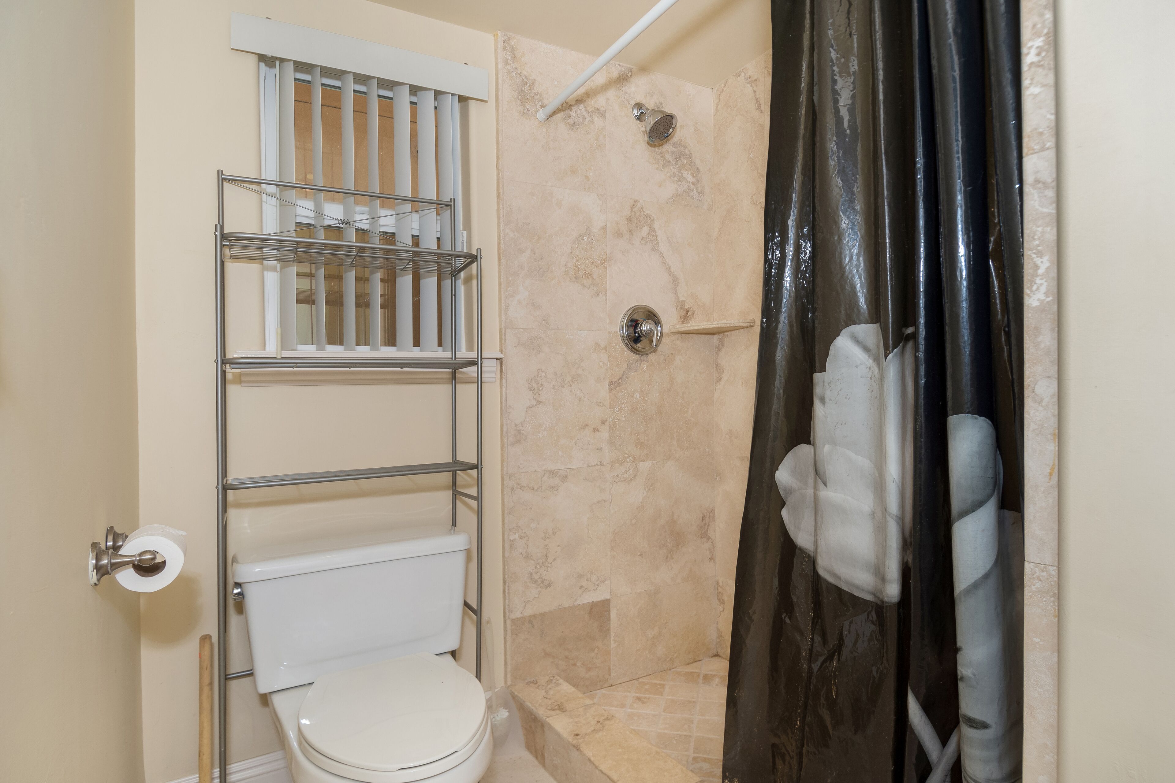 A bathroom with a toilet, a shower with a glass door, and a towel rack.