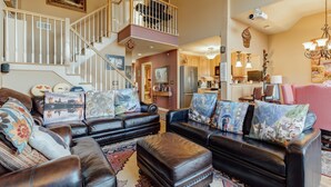 A spacious living room with a staircase leading to an upper level, a kitchen area, and a dining space. - Lakefront 2BR Condo Across from Mtn Creek #09-23 (vernon)