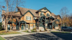 A multi-story log cabin-style building with a steeply pitched roof, multiple chimneys, and a front porch with a staircase. - Lakefront 2BR Condo Across from Mtn Creek #09-23 (vernon)