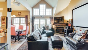 A spacious living room with a fireplace, a dining area, and a large window. - Lakefront 2BR Condo Across from Mtn Creek #09-23 (vernon)