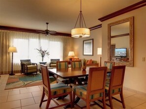 Une salle à manger d’hôtel avec une grande table, plusieurs chaises, un ventilateur de plafond et un téléviseur.
