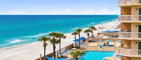 Un hotel con piscina, vistas a la playa y varios balcones.