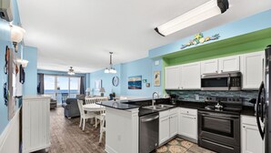 A kitchen with white cabinets, a black countertop, and stainless steel appliances. - AMAZING VIEWS! FREE BEACH SERVICE! (Panama City Beach)