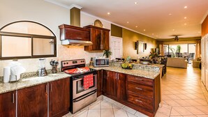 A modern kitchen with dark wood cabinets, a built-in oven, a microwave, and granite countertops. - Sunrise 30, beautiful Condo In the Heart of Town (Tamarindo)