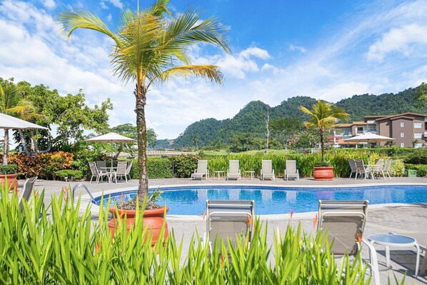 A pool area with lounge chairs, a palm tree, and a view of a mountainous landscape. - Perfect Location, overlooking Greens, access to all amenities. (Herradura)
