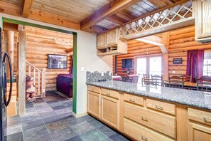 L’intérieur d’un chalet en bois comprend un espace cuisine doté de plans de travail en granit et d’armoires en bois.