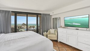 Une chambre d’hôtel avec un grand lit, une télévision, un fauteuil et une vue sur l’océan.