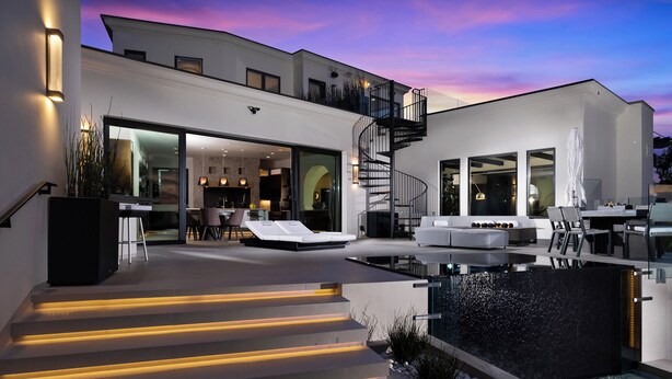 Une maison moderne dotée d’une piscine, d’un espace salon extérieur et d’un escalier dont les marches sont illuminées.