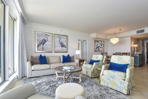 A living room with a sofa, armchairs, a coffee table, and artwork on the walls.