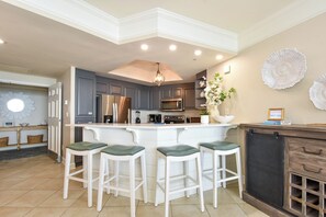 A modern kitchen with a central island, bar stools, and a built-in refrigerator.