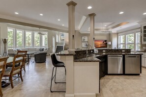 Un'ampia cucina con un'isola grande, elettrodomestici moderni e vista sull'esterno.