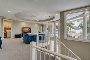 A spacious living room with a large TV, a blue sofa, and a ceiling fan.