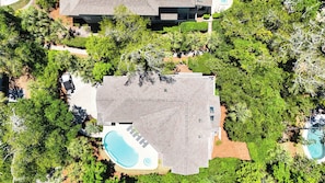 Vue aérienne d’une maison dotée d’une piscine, entourée d’une végétation luxuriante.