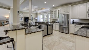 Eine moderne Küche mit Granit Arbeitsplatten, Edelstahlgeräten und weißen Schränken.
