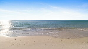 A beach with clear water and a sandy shore under a blue sky. - Regency Isle 507 by Liquid Life (Orange Beach)