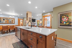 A modern kitchen with a central island, wooden cabinetry, and a dining area with a bench.