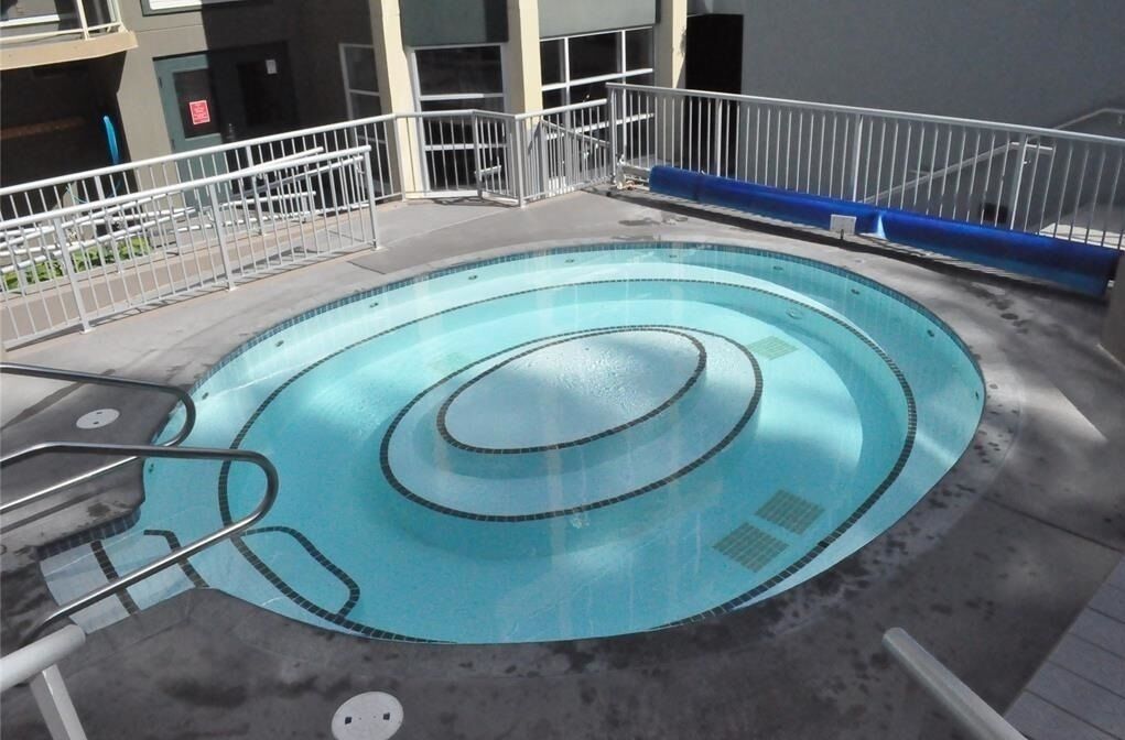 Ein runder Pool mit spiralförmigem Design, umgeben von einem weißen Metallgeländer und einer Betonplattform.