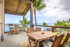 Een houten terras met een tafel en stoelen met uitzicht op een strand.