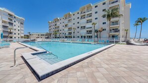 Un hotel con piscina, varios balcones y palmeras.